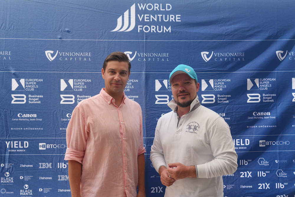 Zwei Männer (Die Stiftungsvorstände Alexander Rapatz und Berthold Baurek-Karlic) vor der World Venture Forum Logo Wall